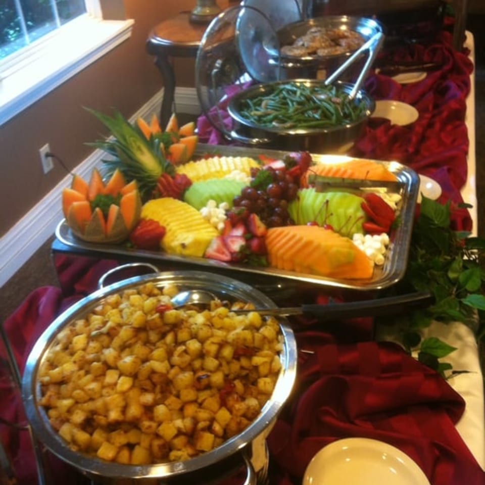 A buffet spread with soul food dishes, including roasted potatoes, green beans, and a fruit platter.