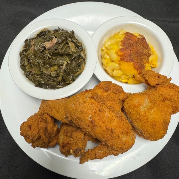 Fried chicken wings, collard greens, and baked macaroni and cheese on a white plate.
