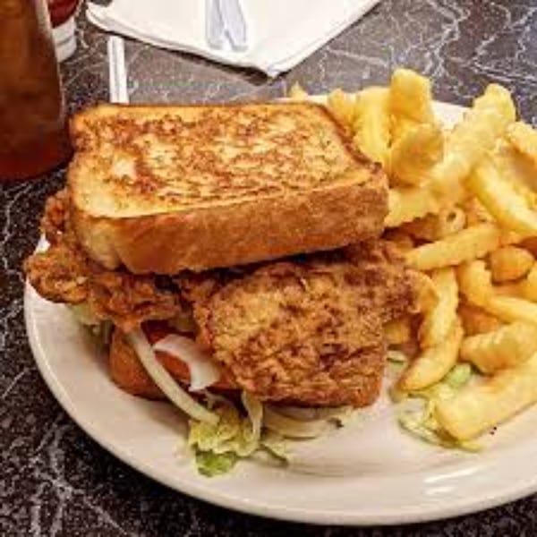 Crispy fried chicken sandwich with lettuce, tomato, and onions, served with a side of french fries.